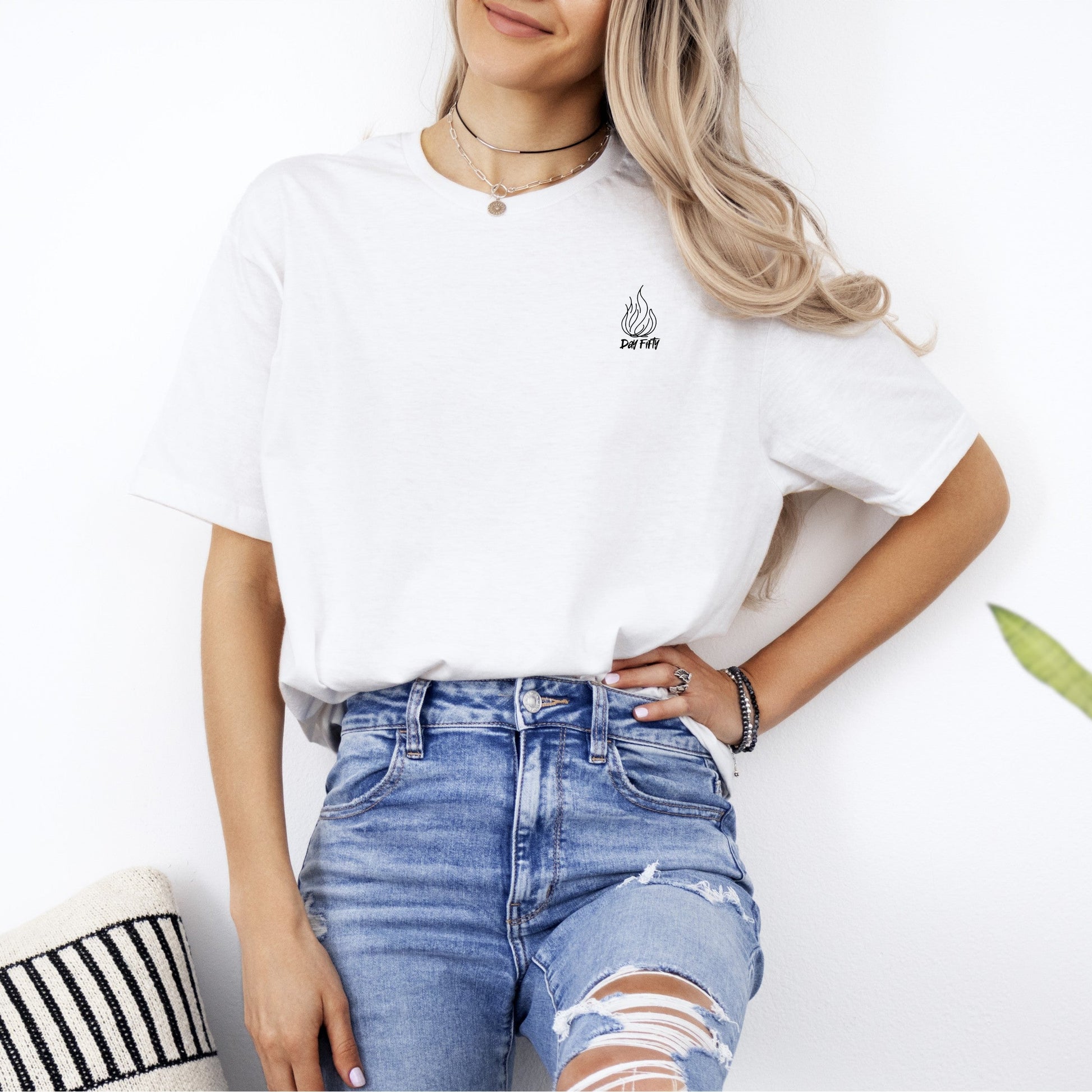Person wearing a white t-shirt and ripped jeans standing against a white background