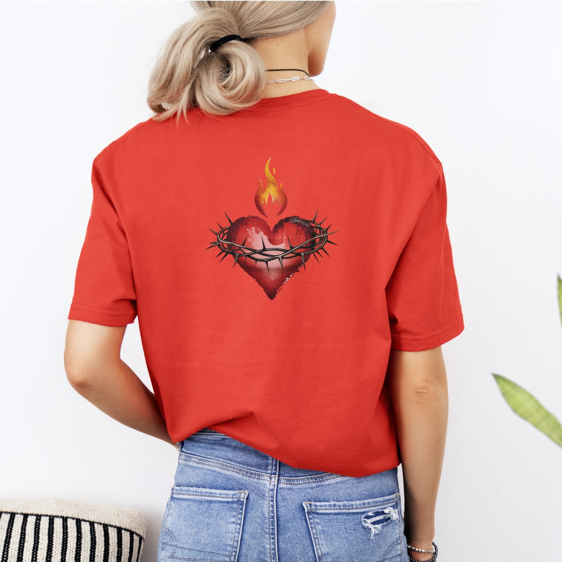 Person wearing a red t-shirt with a heart design on the back, standing against a white background.